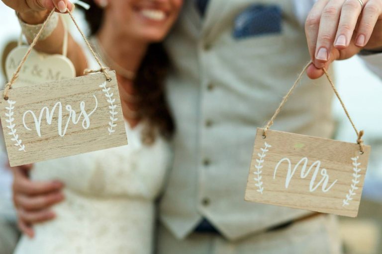 A couple at their wedding holding up signs for their mr and mrs quiz questions