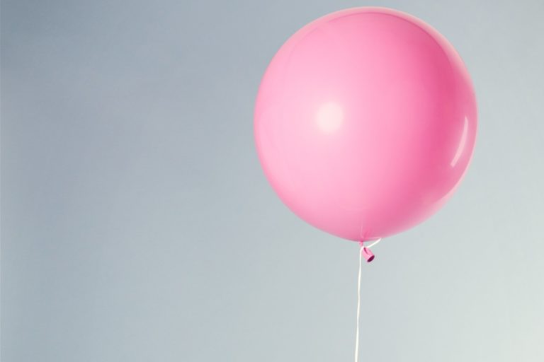 A pink balloon tied to a chair for a hen party balloon pop game