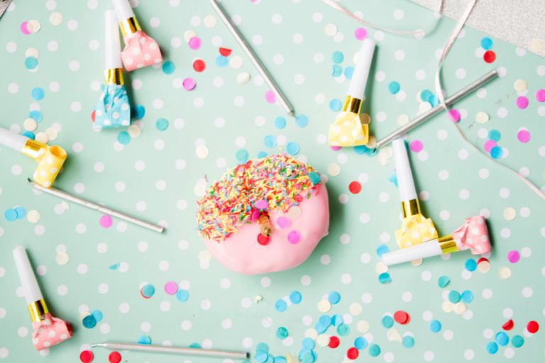 Confetti, party blowers and food sitting on a blue table cover