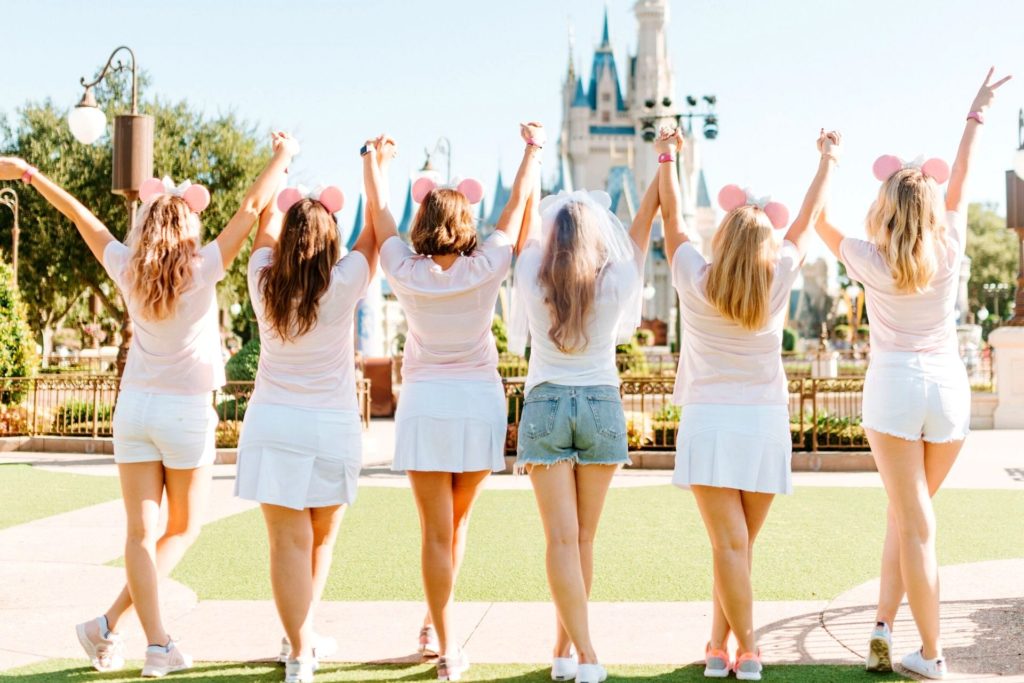 A bride and five bridesmaids standing in front of the Disneyworld castle at the theme park