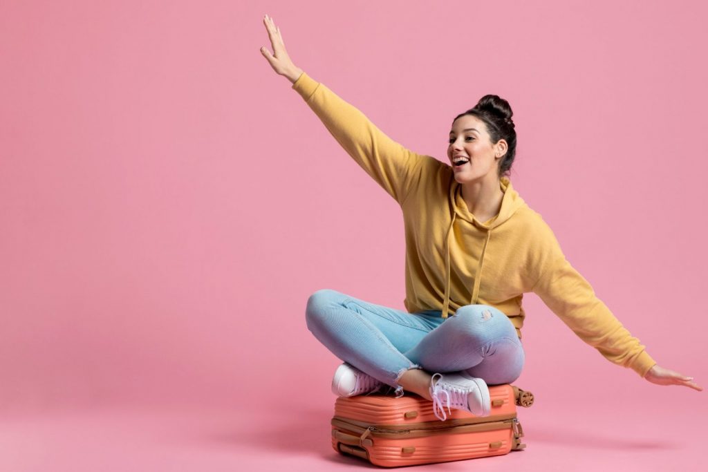 Girl sitting on top of a suitcase