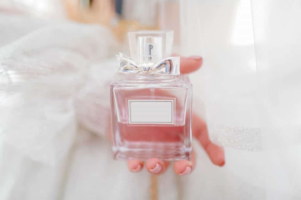 Bride holding up a perfume bottle as a classy hen party idea