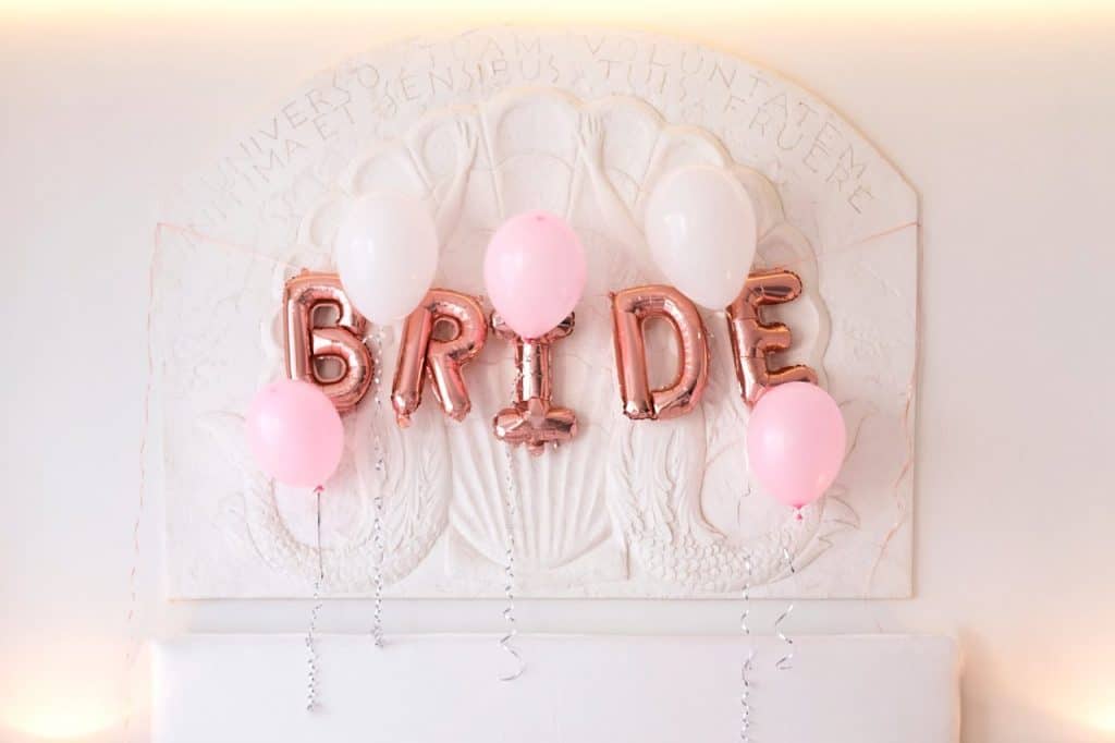 Pink balloons that spell out the word bride hanging on a wall as a type of hen party quotes